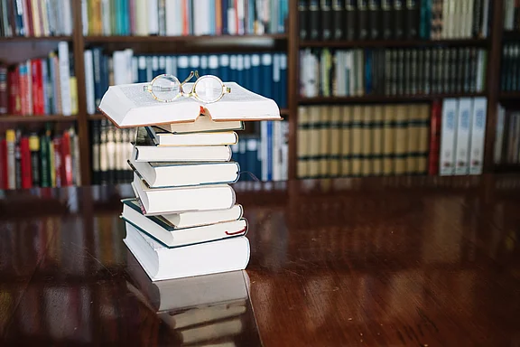 Bücher und Brille auf einem Tisch – der Leitfaden DIN SPEC 91524 für Compliance in KMU